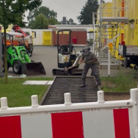 Ein Bauarbeiter entfernt Bordsteine, damit ein Bagger dadurch fahren kann