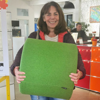 Eine glückliche Frau mit einem grünen Hocker in den Händen