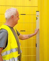 Ein Mitarbeiter prüft mithilfe einer Wasserwaage den aufgestellten Container auf gerade Positionierung 