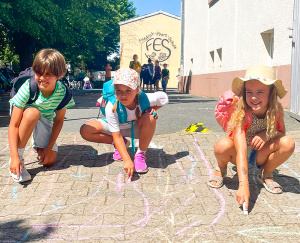 Kartierung der Schulwege: Luan, Elena und Zoé zeigen mit bunten Kreidesymbolen ihren Schulweg