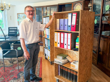 Dr. Martin Zentgraf, Vorstand Hessischer Diakonieverein e.V., steht lachend in seinem alten Büro vor dem antiken Schrank